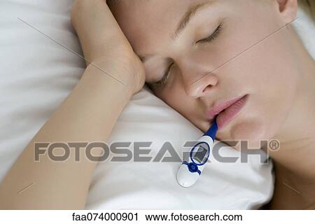 Young woman checking temperature with thermometer View Large Photo Image Stock Image - Young woman checking temperature with thermometer. Fotosearch