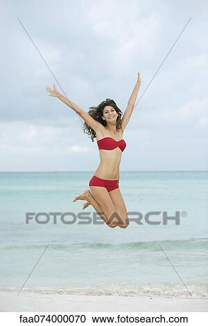 Young woman in bikini jumping in midair at the beach View Large Photo Image Stock Image - Young woman in bikini jumping in midair at the beach. Fotosearch