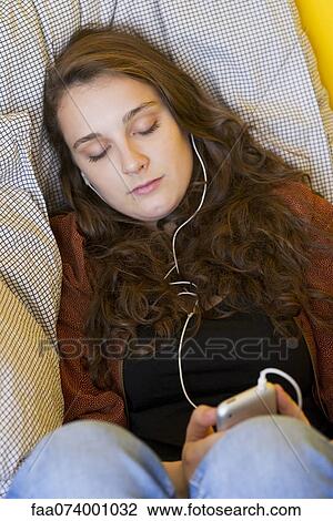 Young woman listening to MP3 player with eyes closed View Large Photo Image Stock Image - Young woman listening to MP3 player with eyes closed. Fotosearch