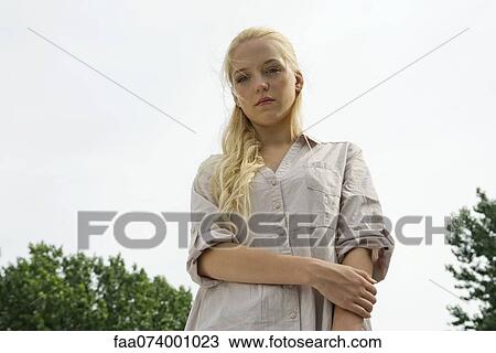 Stock Image - Young woman looking at camera with sad expression. Fotosearch