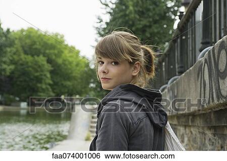 Young woman looking over shoulder, portrait View Large Photo Image Stock Photograph - Young woman looking over shoulder, portrait. Fotosearch