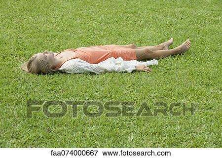 Young woman napping on grass View Large Photo Image Stock Photo - Young woman napping on grass. Fotosearch