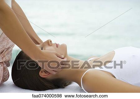 Stock Photo - Young woman receiving face massage, side view. Fotosearch