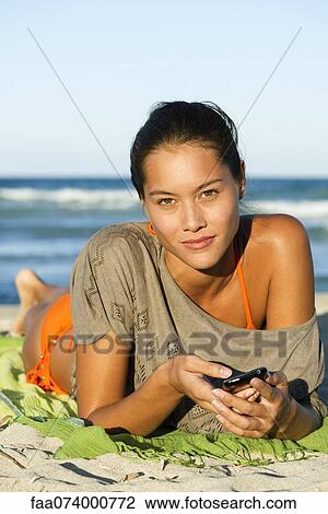 Stock Image - Young woman relaxing on beach, portrait. Fotosearch
