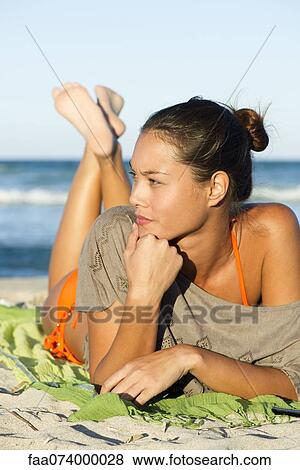 Stock Photo - Young woman relaxing on beach, portrait. Fotosearch