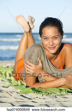 Stock Photo - Young woman relaxing on beach, portrait. Fotosearch