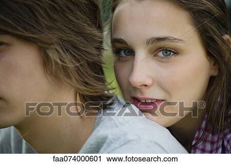 Stock Image - Young woman resting head on boyfriend's shoulder, cropped portrait. Fotosearch