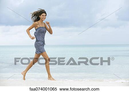Stock Photography - Young woman running at the beach. Fotosearch