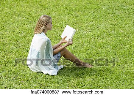 Young woman sitting on grass reading book View Large Photo Image Stock Photo - Young woman sitting on grass reading book. Fotosearch