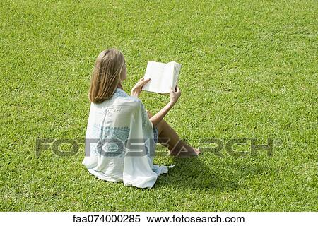 Young woman sitting on grass reading book View Large Photo Image Stock Photography - Young woman sitting on grass reading book. Fotosearch