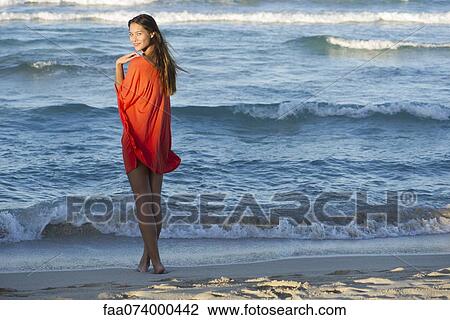 Stock Image - Young woman standing on beach. Fotosearch