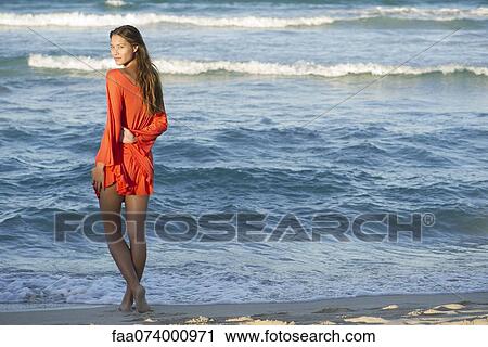 Stock Image - Young woman standing on beach. Fotosearch