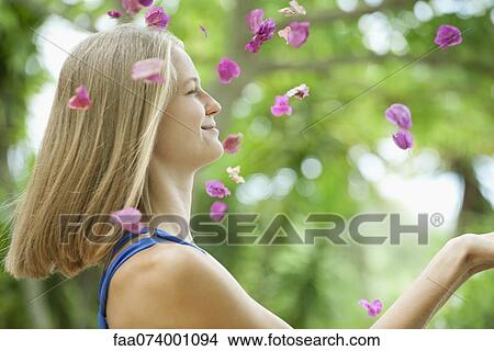 Young woman throwing petals in air, side view View Large Photo Image Picture - Young woman throwing petals in air, side view. Fotosearch