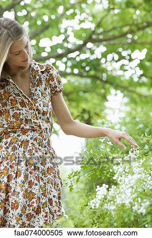 Stock Photography - Young woman touching wildflowers. Fotosearch