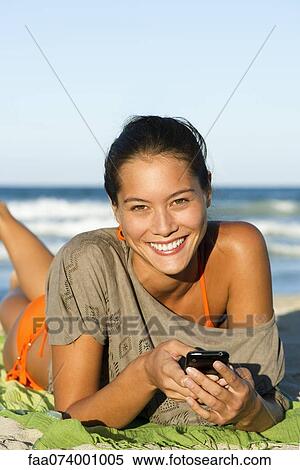 Young woman using cell phone on beach, portrait View Large Photo Image Stock Photography - Young woman using cell phone on beach, portrait. Fotosearch