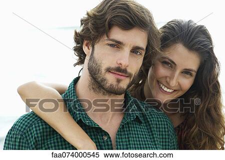 Stock Photography - Young woman with arm around boyfriend, portrait. Fotosearch