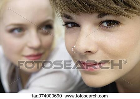 Stock Image - Young woman with friend, smiling, portrait. Fotosearch