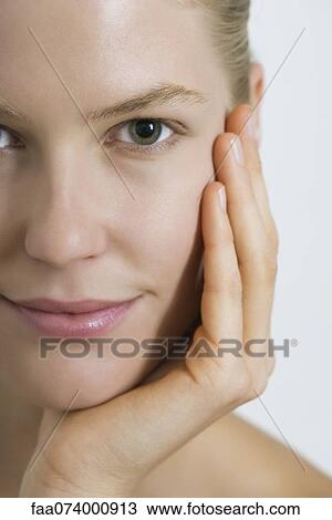 Stock Image - Young woman with hand under chin, close-up. Fotosearch