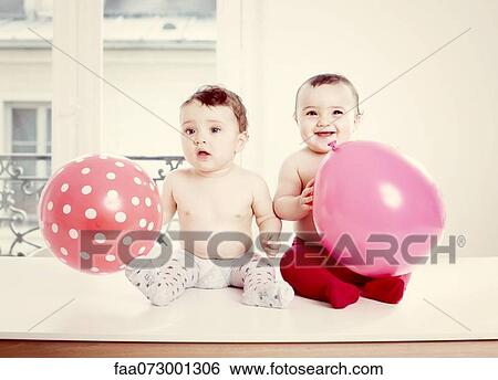 Stock Photograph - Baby girls with balloons, portrait. Fotosearch