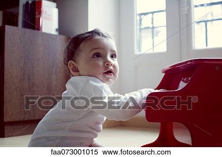 Stock Photography - Baby playing with toy piano, portrait. Fotosearch