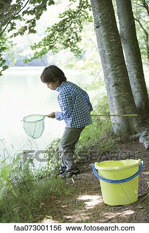 Boy catching tadpoles at water's edge View Large Photo Image Stock Photograph - Boy catching tadpoles at water's edge. Fotosearch