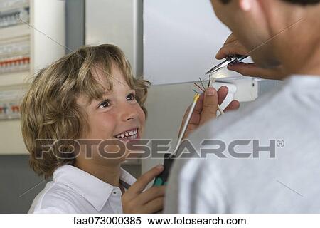 Stock Photography - Boy helping father fixing wires. Fotosearch