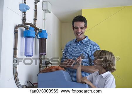 Boy helping father repair home water filtration system View Large Photo Image Stock Photo - Boy helping father repair home water filtration system. Fotosearch