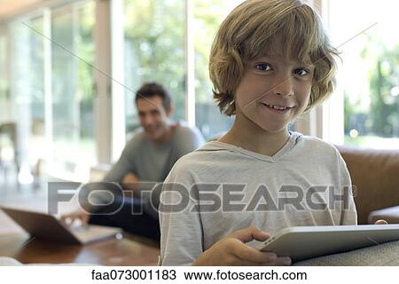 Boy holding digital tablet in living room View Large Photo Image Stock Image - Boy holding digital tablet in living room. Fotosearch