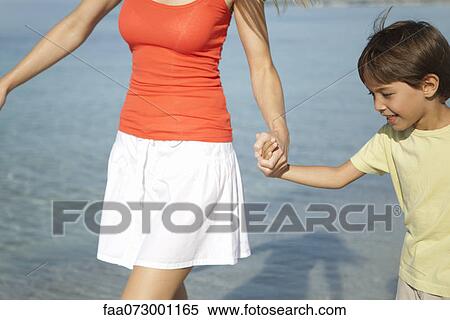 Stock Photography - Boy holding his mother's hand at the beach. Fotosearch