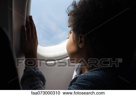 Stock Image - Boy looking out airplane window. Fotosearch