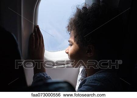 Boy looking out airplane window View Large Photo Image Stock Photograph - Boy looking out airplane window. Fotosearch
