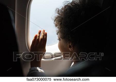Stock Photography - Boy looking out airplane window. Fotosearch