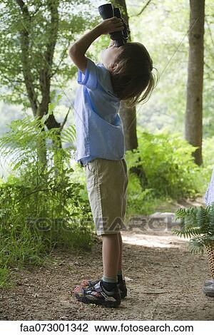 Boy looking through binoculars in woods View Large Photo Image Stock Image - Boy looking through binoculars in woods. Fotosearch