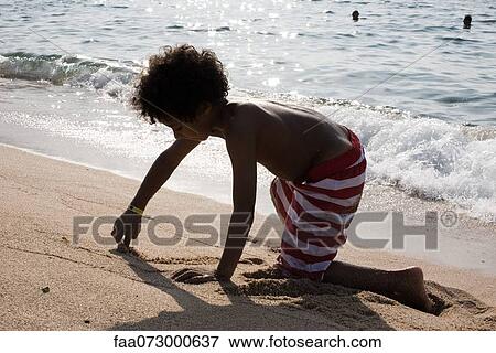 Boy playing in sand at the beach View Large Photo Image Stock Photo - Boy playing in sand at the beach. Fotosearch