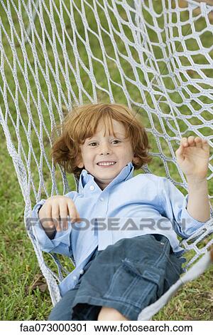 Stock Image - Boy relaxing in hammock, portrait. Fotosearch