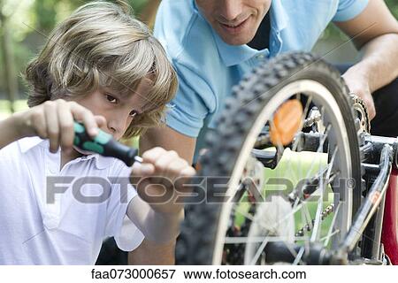 Boy repairing bicycle with father's help View Large Photo Image Stock Photo - Boy repairing bicycle with father's help. Fotosearch