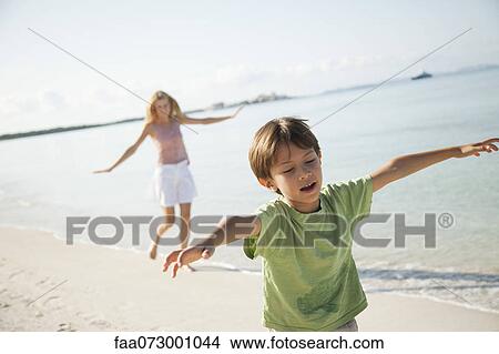 Picture - Boy running with arms out at the beach. Fotosearch