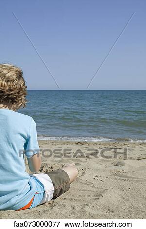 Boy sitting on beach, looking at sea View Large Photo Image Stock Photo - Boy sitting on beach, looking at sea. Fotosearch