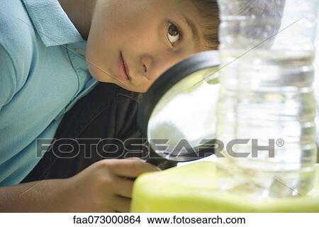 Boy studying bottle of water with magnifying glass View Large Photo Image Picture - Boy studying bottle of water with magnifying glass. Fotosearch