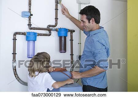 Boy watching father repairing home water filtration system View Large Photo Image Stock Photo - Boy watching father repairing home water filtration system. Fotosearch
