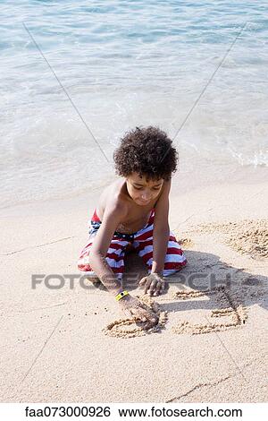 Boy writing in sand at the beach View Large Photo Image Stock Photograph - Boy writing in sand at the beach. Fotosearch