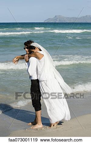 Bride and groom embracing at the beach View Large Photo Image Stock Photo - Bride and groom embracing at the beach. Fotosearch