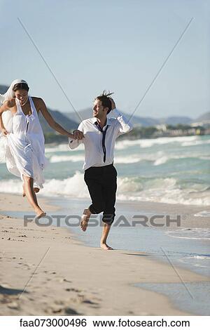 Bride and groom running hand and hand at the beach View Large Photo Image Stock Photograph - Bride and groom running hand and hand at the beach. Fotosearch