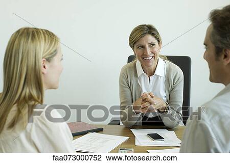 Businesswoman talking with clients in office View Large Photo Image Stock Image - Businesswoman talking with clients in office. Fotosearch