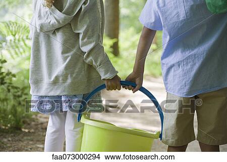 Children carrying bucket together, cropped View Large Photo Image Picture - Children carrying bucket together, cropped. Fotosearch