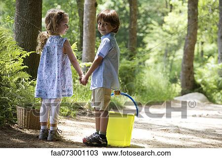 Stock Image - Children holding hands on path in woods. Fotosearch