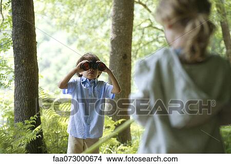 Children in woods, boy looking through binoculars View Large Photo Image Picture - Children in woods, boy looking through binoculars. Fotosearch