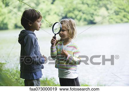 Children playing with magnifying glass outdoors View Large Photo Image Stock Photo - Children playing with magnifying glass outdoors. Fotosearch