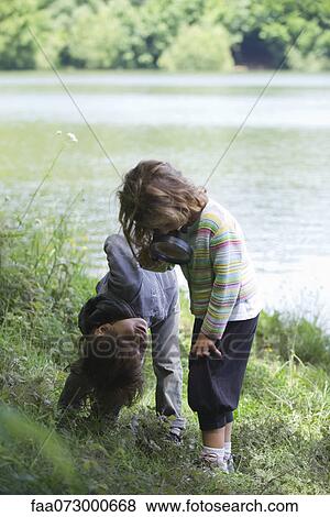 Stock Photo - Children playing with magnifying glass outdoors. Fotosearch