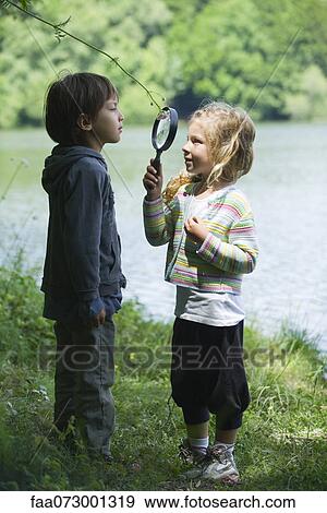 Stock Photo - Children playing with magnifying glass outdoors. Fotosearch